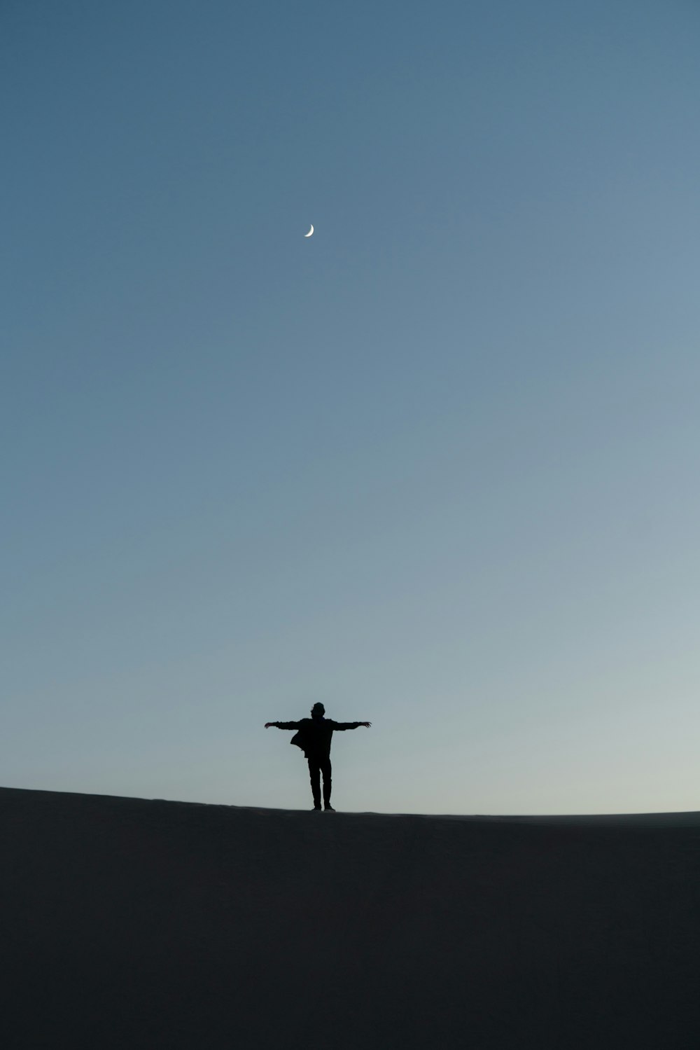 silhouette of person standing on the ground under blue sky during daytime