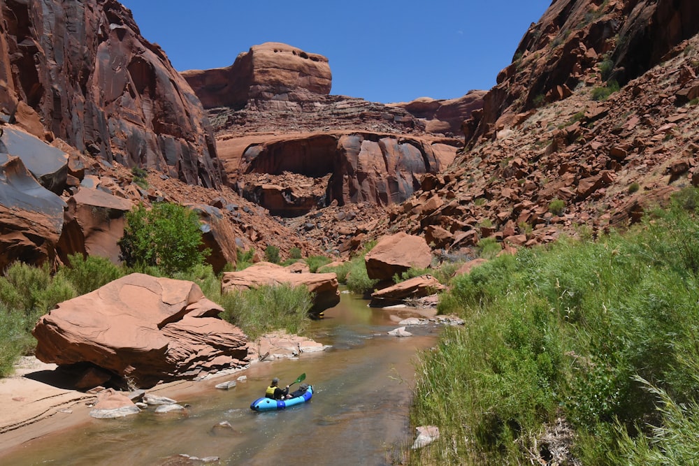 person in blue kayak on river during daytime