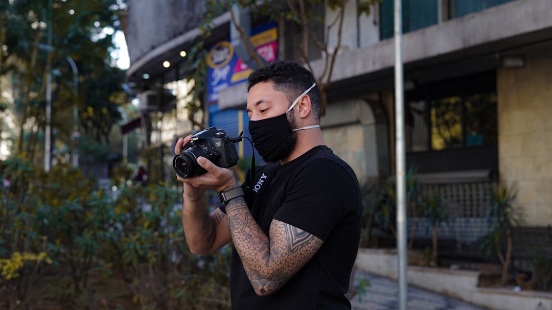 man in black crew neck t-shirt holding black dslr camera