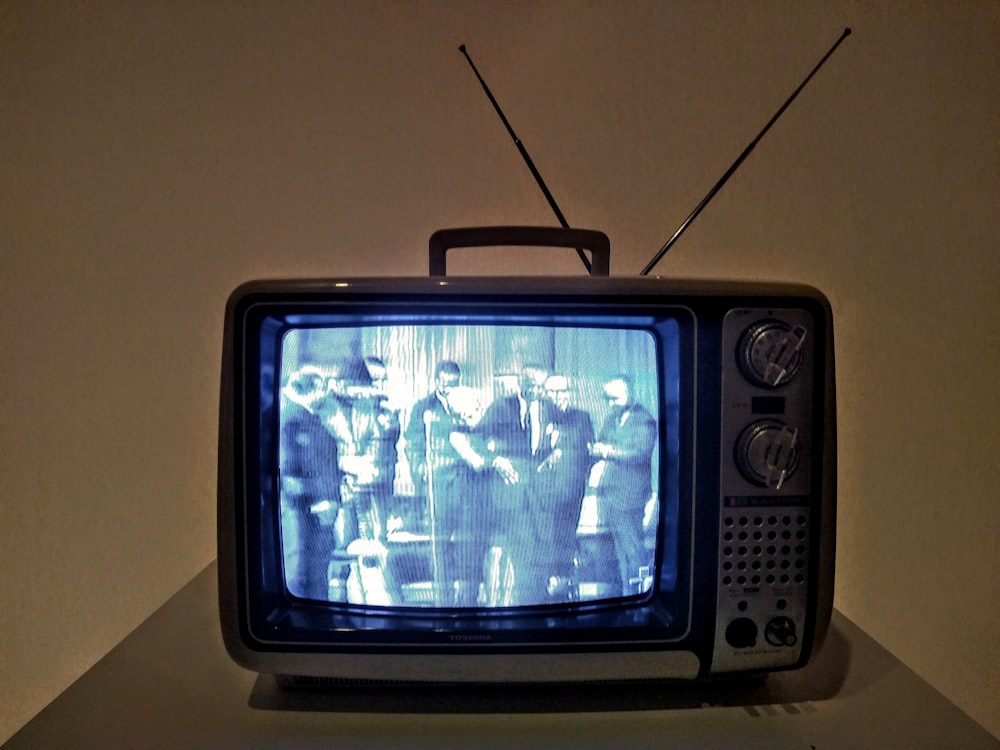 Schwarzer CRT-Fernseher auf weißem Tisch eingeschaltet