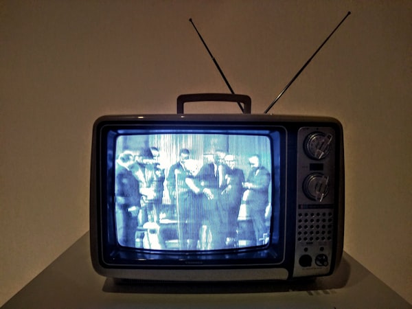Photo of an old TV (rabbit ears, channel knobs, etc) with a grainy black-and-white image on the screen.