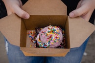A delivery person handing over a sweet box at a doorstep.