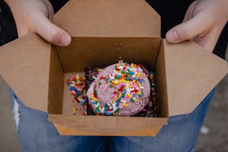 A delivery person handing over a sweet box at a doorstep.