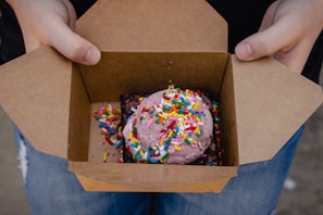 A smiling customer holding a box of Gala Gourmet brownies outside a local store.