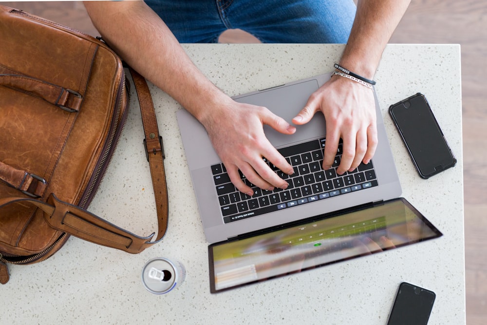 person using macbook pro on brown wooden table