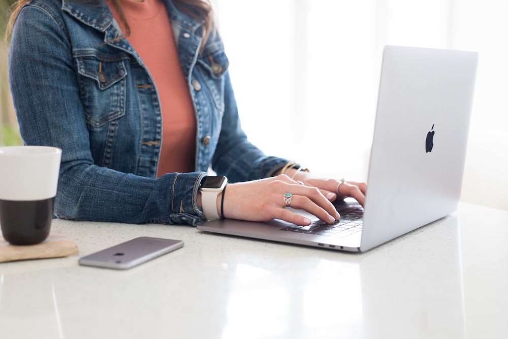 woman in blue denim jacket using macbook pro