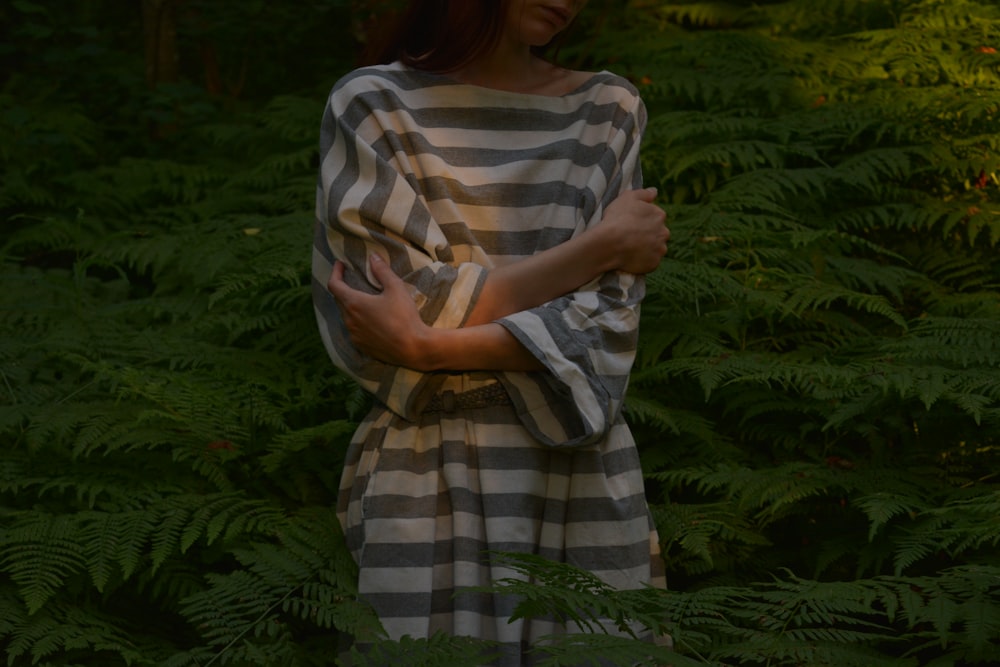 woman in white and brown stripe dress standing near green plants