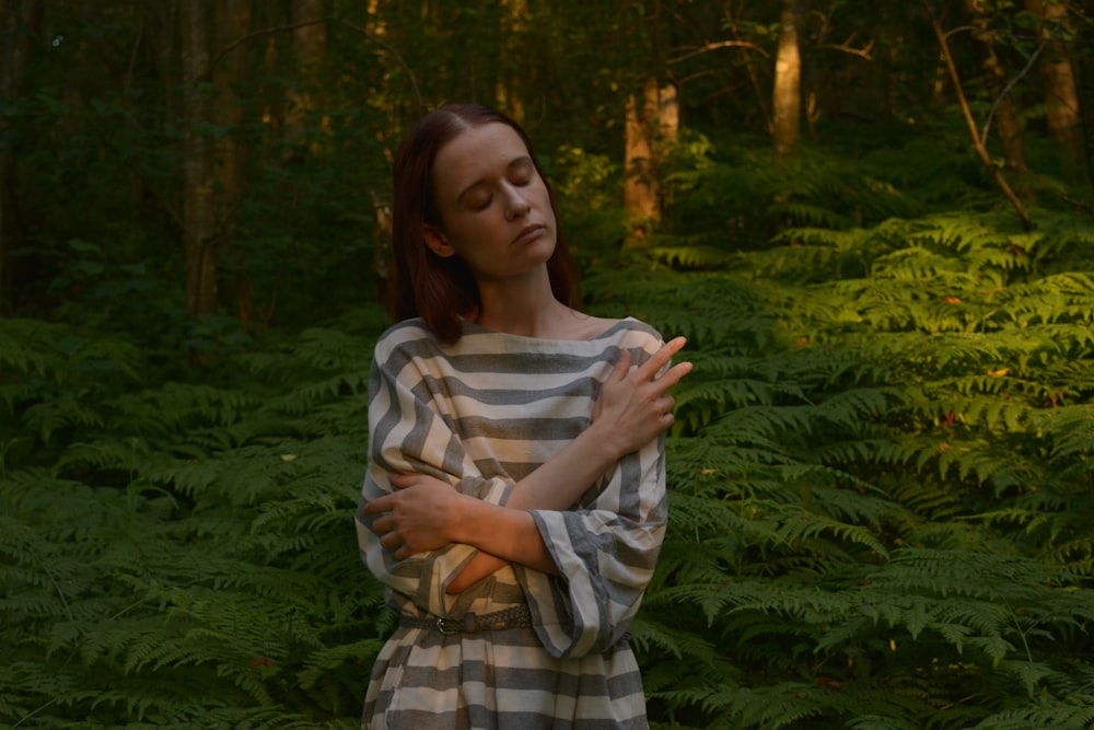 woman in white and brown plaid long sleeve shirt standing in forest