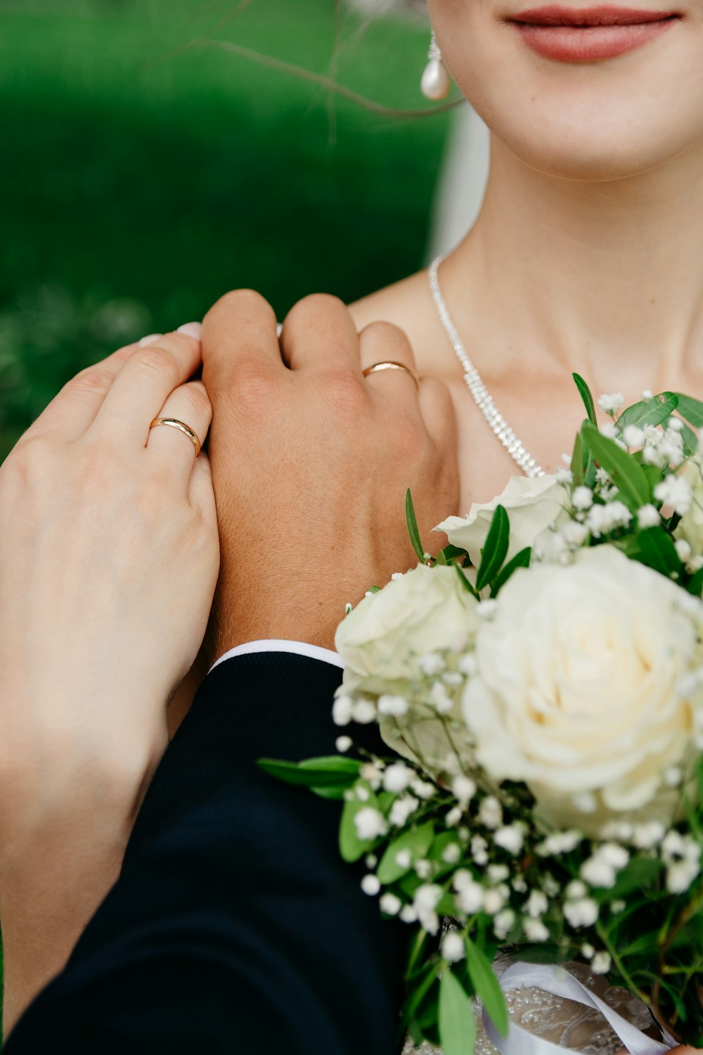 woman in white flower necklace and black dress holding white rose bouquet