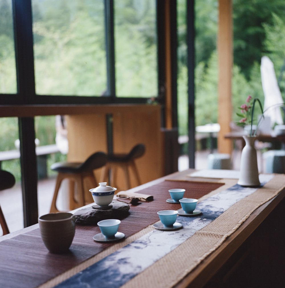 brown wooden table with white ceramic bowl and saucer