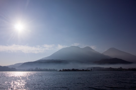 body of water near mountain under blue sky during daytime in Lake Atitlán Guatemala