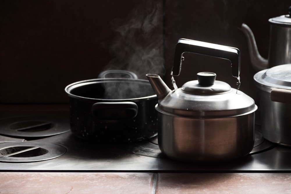 stainless steel kettle beside black ceramic mug on white table