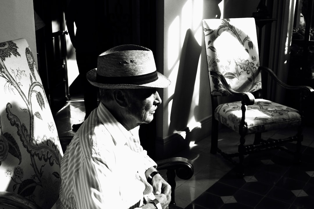 man in white dress shirt and black fedora hat sitting on chair