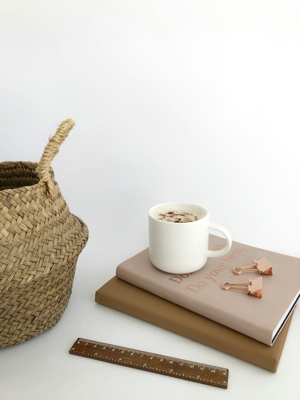 white ceramic mug on white book beside brown woven basket