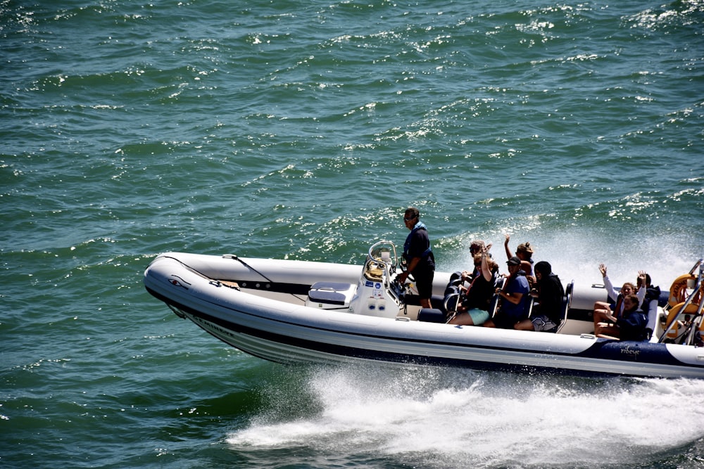 people riding on white and black speed boat on sea during daytime