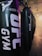A row of black punching bags hangs in a gym, with clear branding on the front. The gym has an industrial vibe with exposed ceilings and a mix of artificial lighting adding purplish and yellowish hues.