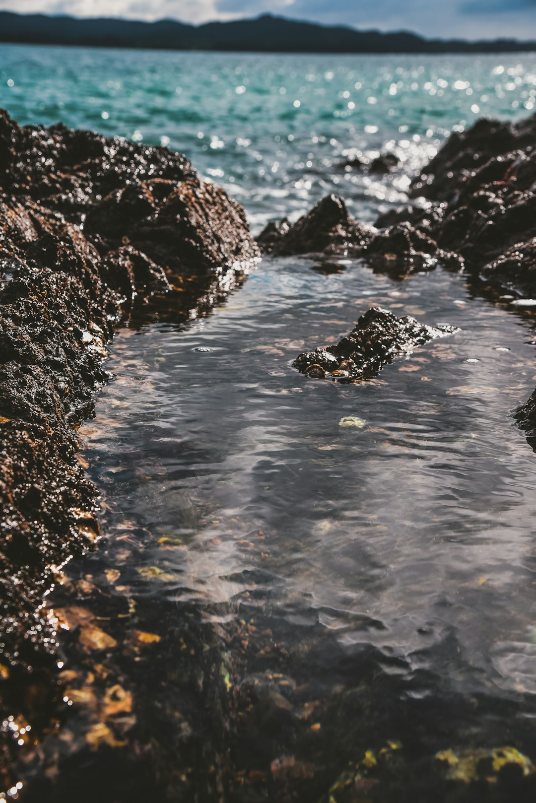 black rock formation on body of water during daytime