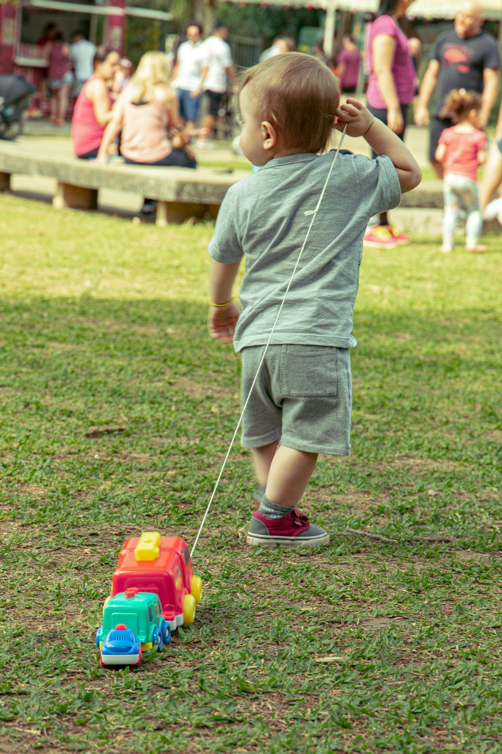 boy in grey t-shirt and grey shorts playing with red and yellow toy car on on on on on