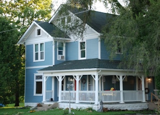 white and gray wooden house near green trees during daytime