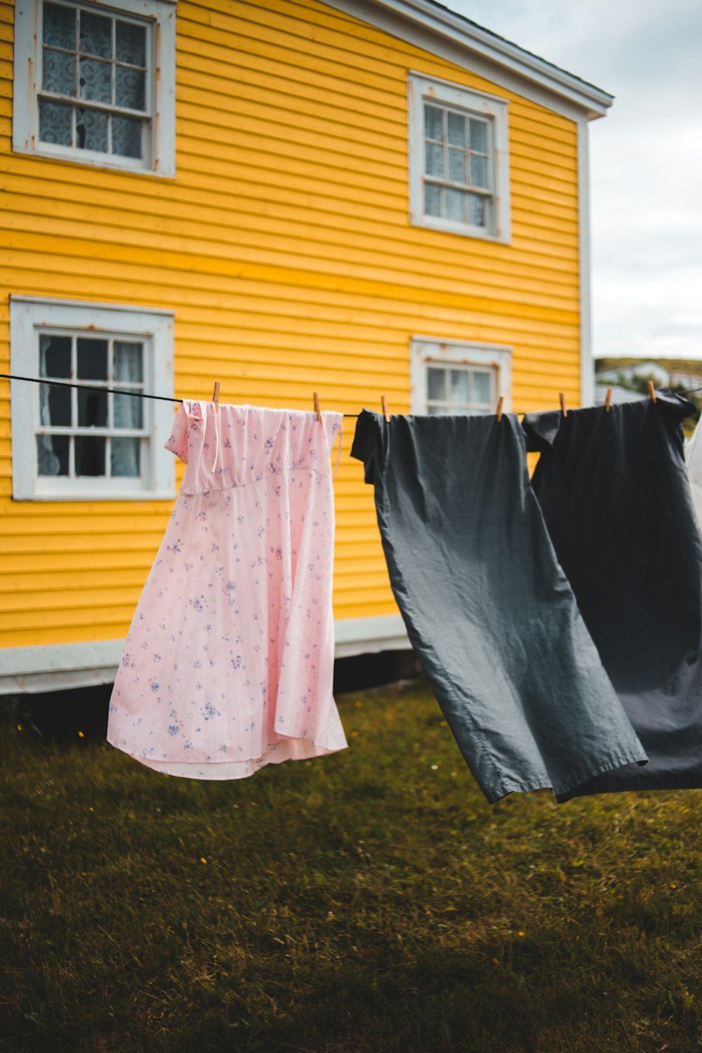 clothes hanging on a clothes line in front of a yellow house