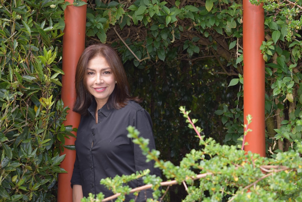 Mujer con polo negro de pie junto a plantas verdes