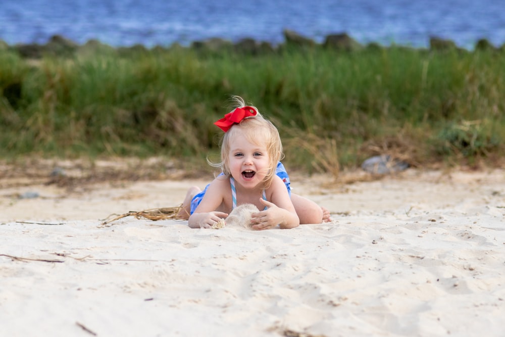 menina na faixa de cabeça vermelha sentada na areia durante o dia
