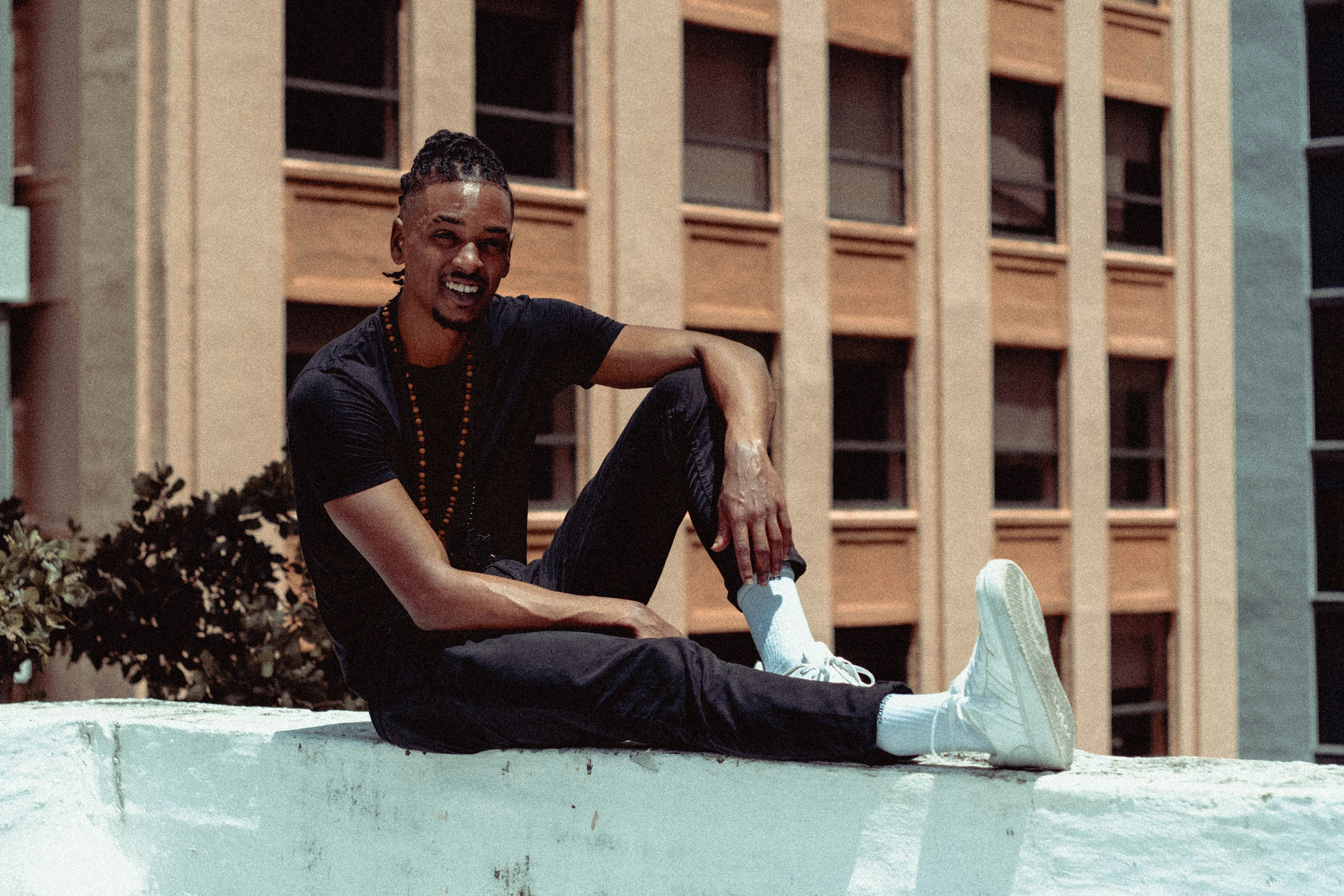 man in black shirt and blue denim jeans sitting on blue concrete bench