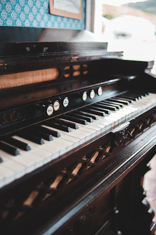 Vintage upright piano mid-restoration showcasing fine woodwork details in a softly lit studio.
