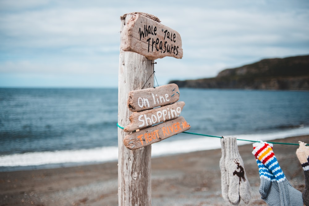 brown wooden beach signage on beach during daytime