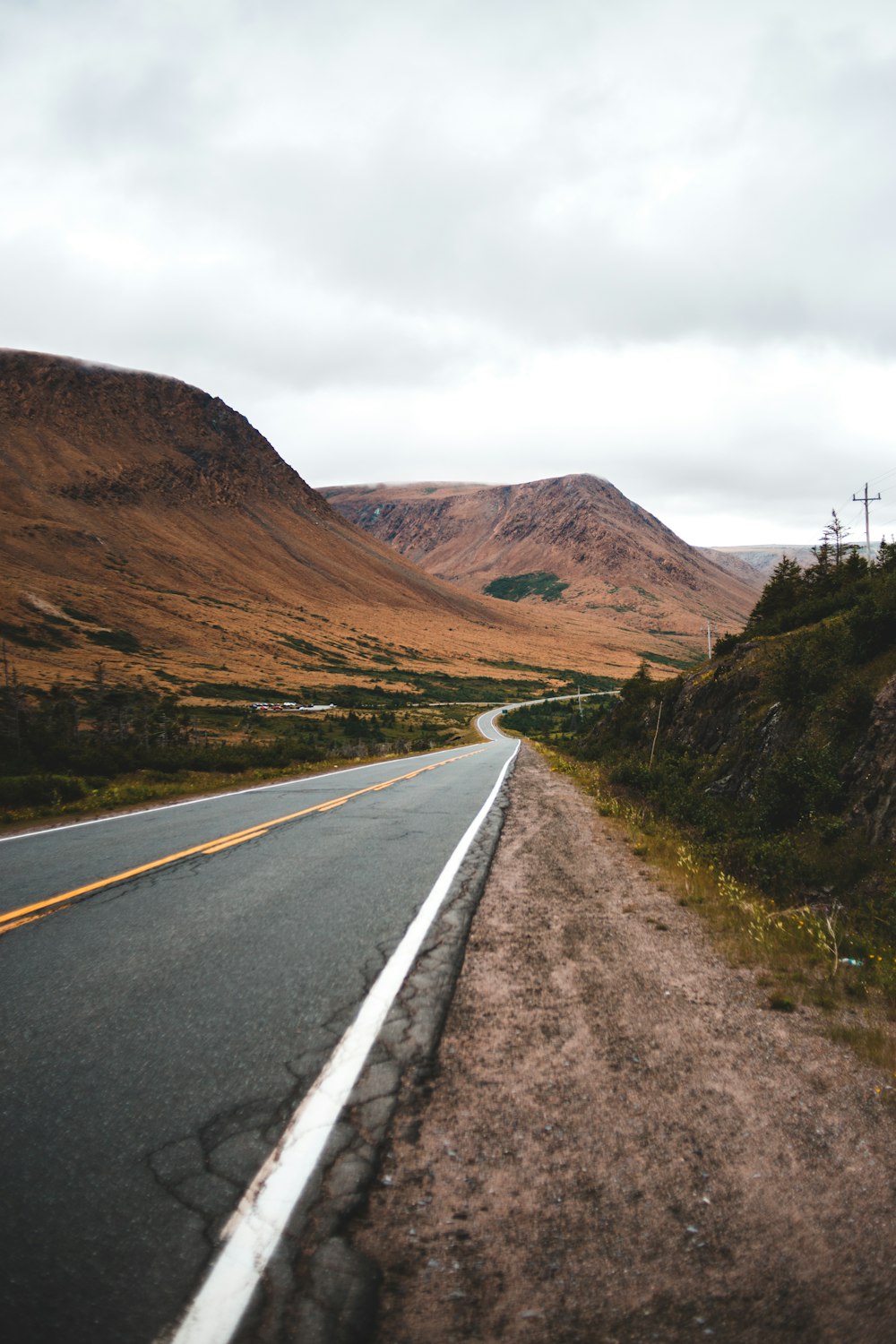 gray concrete road between brown mountains during daytime