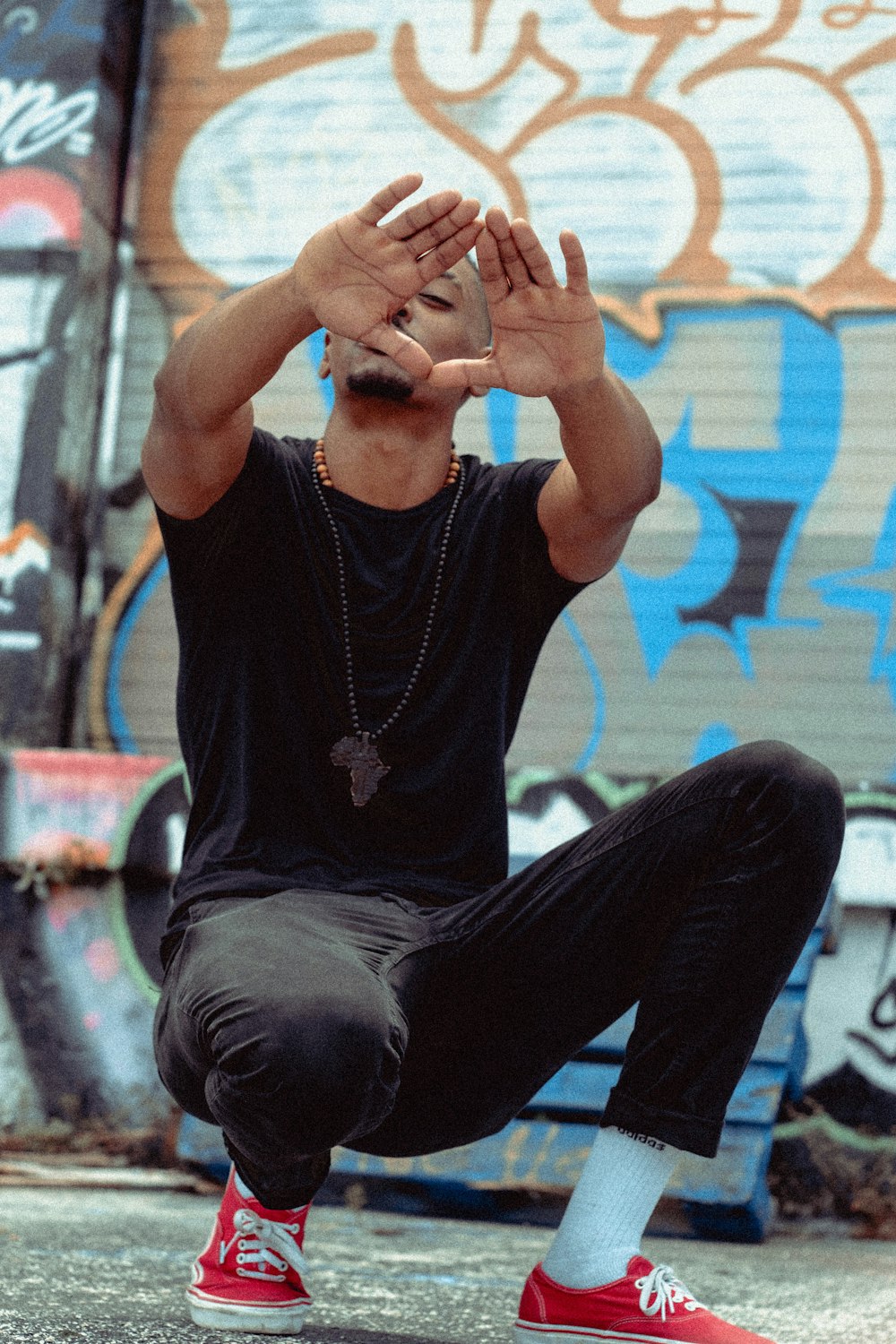 man in black long sleeve shirt and blue denim jeans sitting on blue and white wall