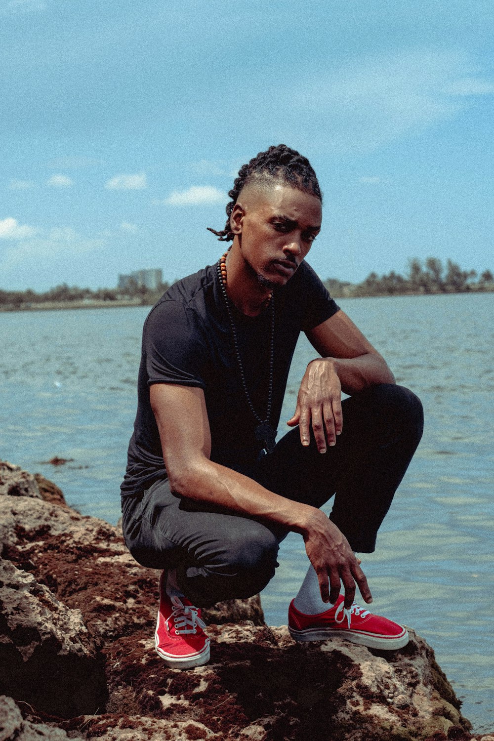 a man sitting on top of a rock next to a body of water