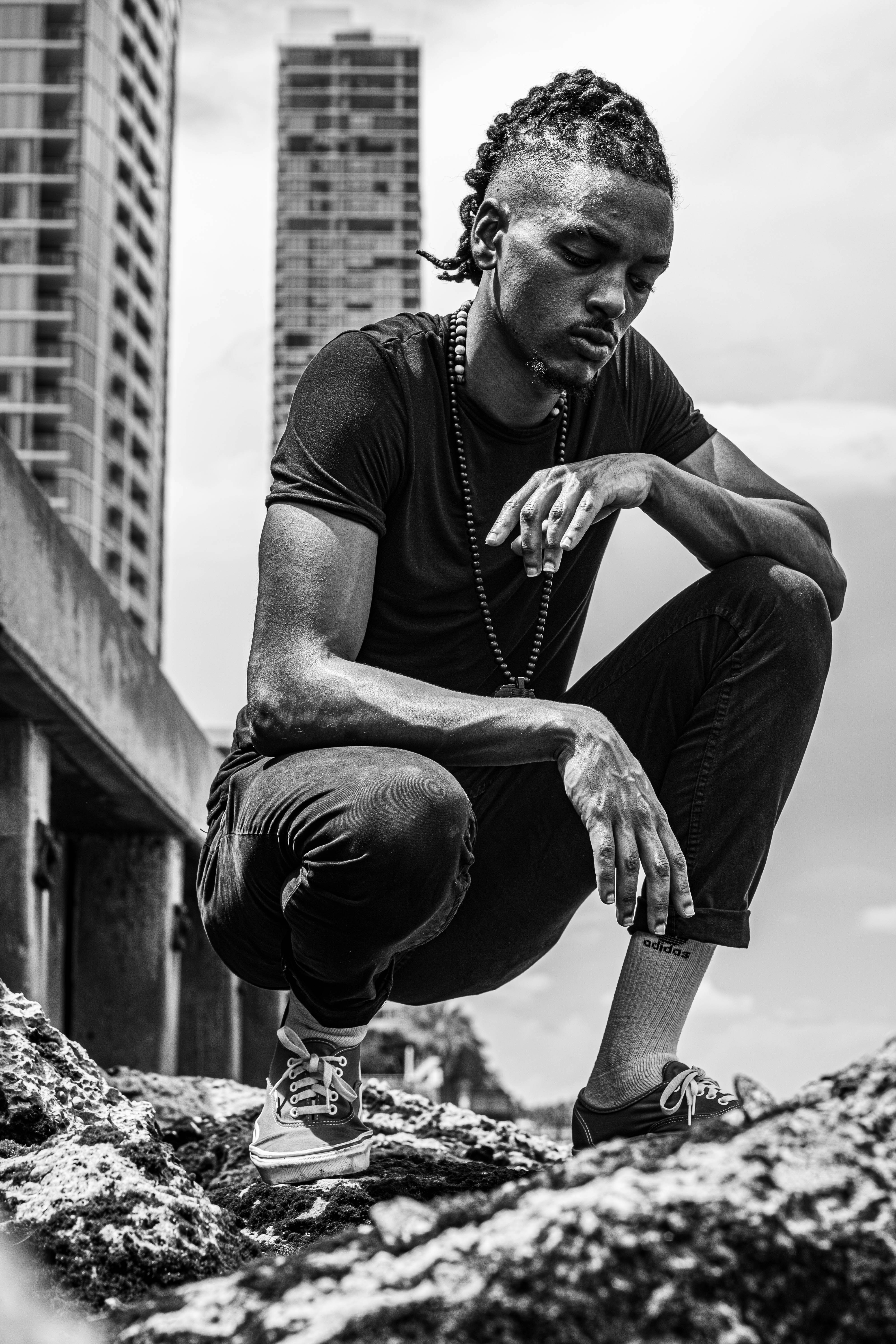 man in black tank top and pants sitting on rock