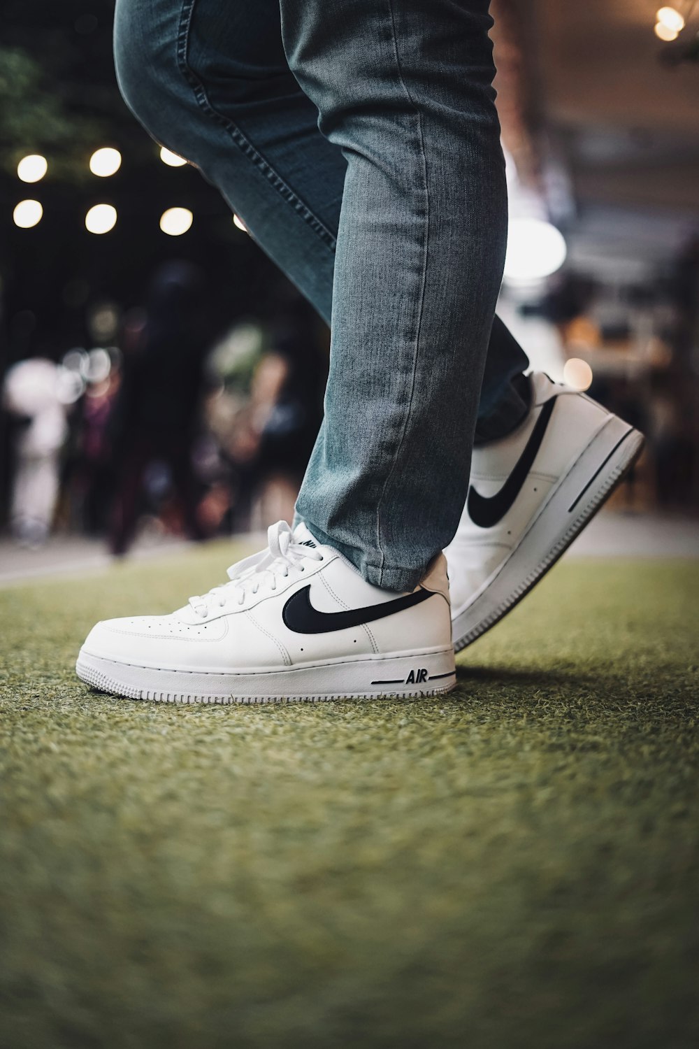 person in blue denim jeans wearing white nike sneakers