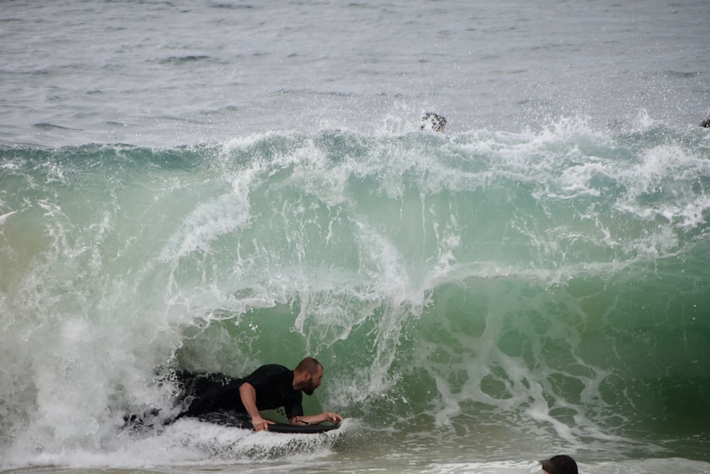 man and woman surfing on sea waves during daytime