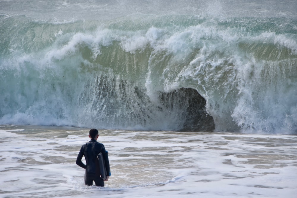 man in black jacket standing on sea shore
