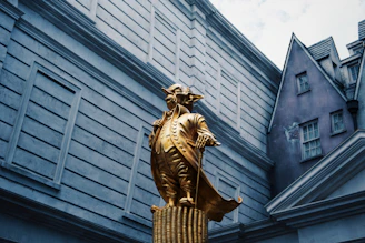 gold statue of man in front of gray concrete building