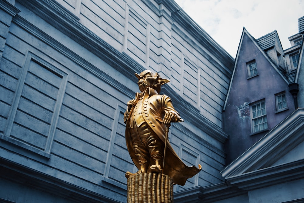 gold statue of man in front of gray concrete building