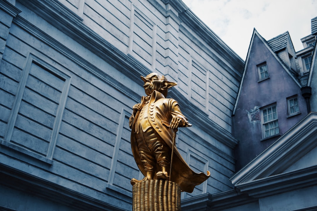 gold statue of man in front of gray concrete building
