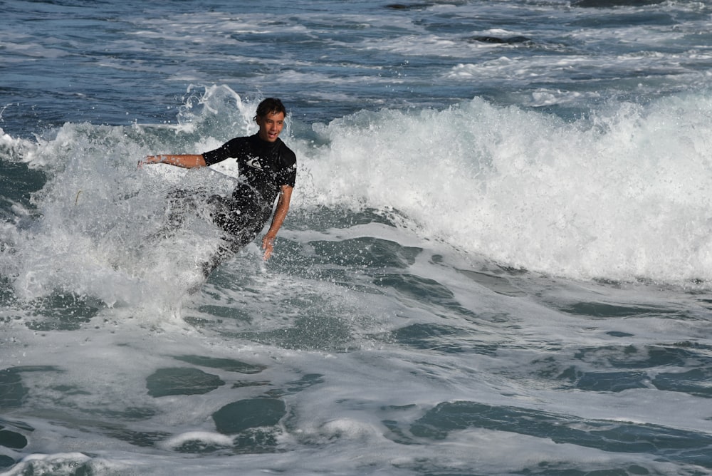 Mann im schwarzen Hemd beim Surfen auf Meereswellen tagsüber