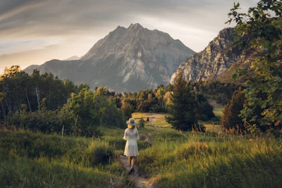 Person standing in a grass field near mountains