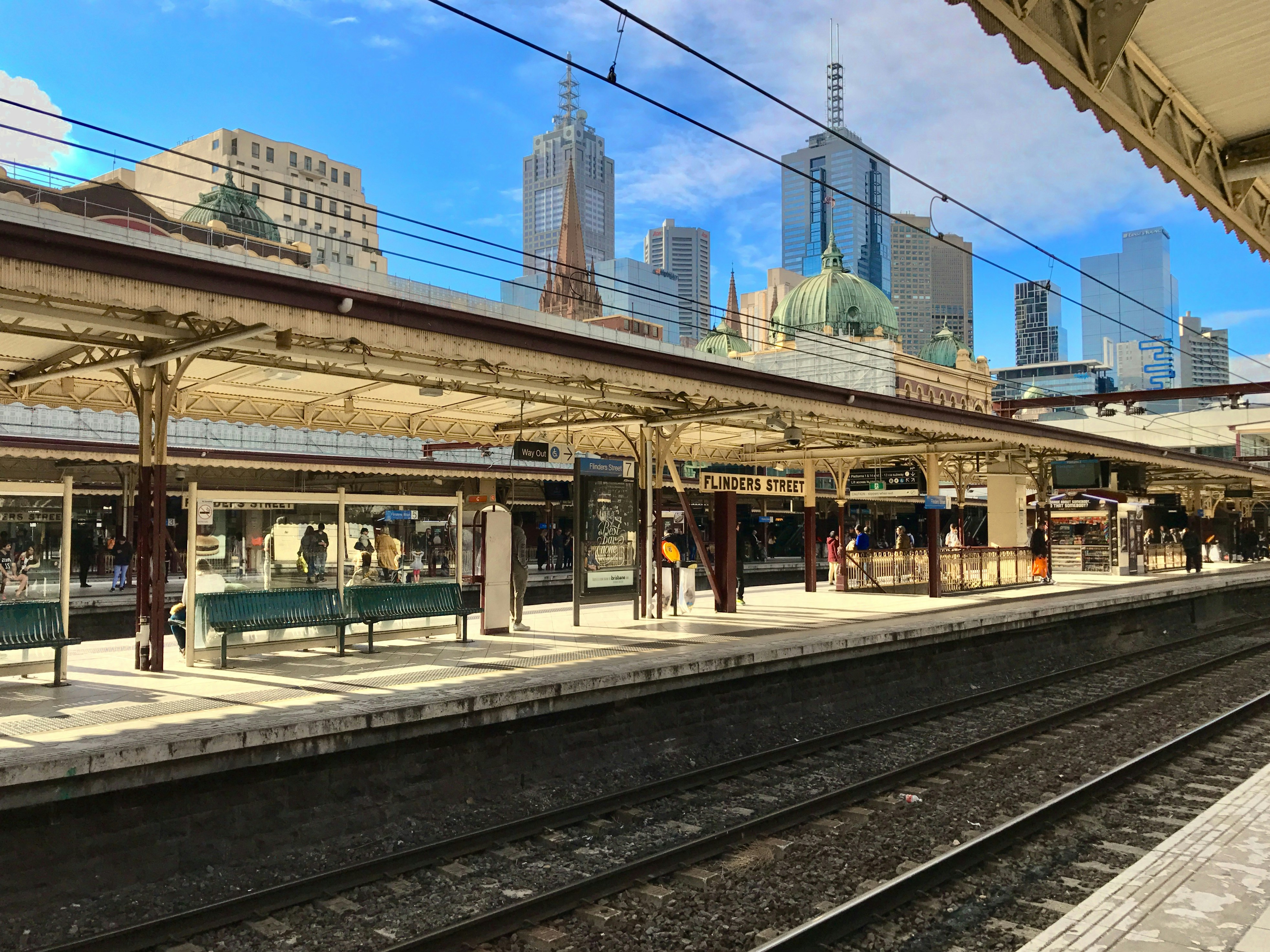 Personas que caminan por la acera cerca de los rieles del tren durante el día