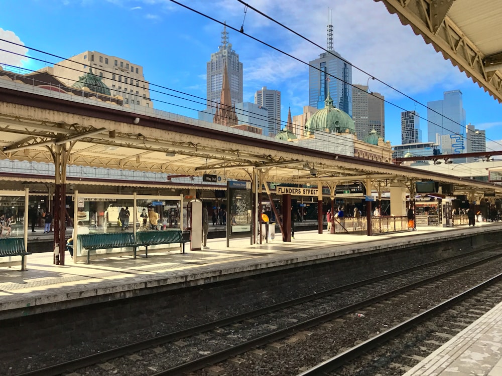 people walking on sidewalk near train rail during daytime