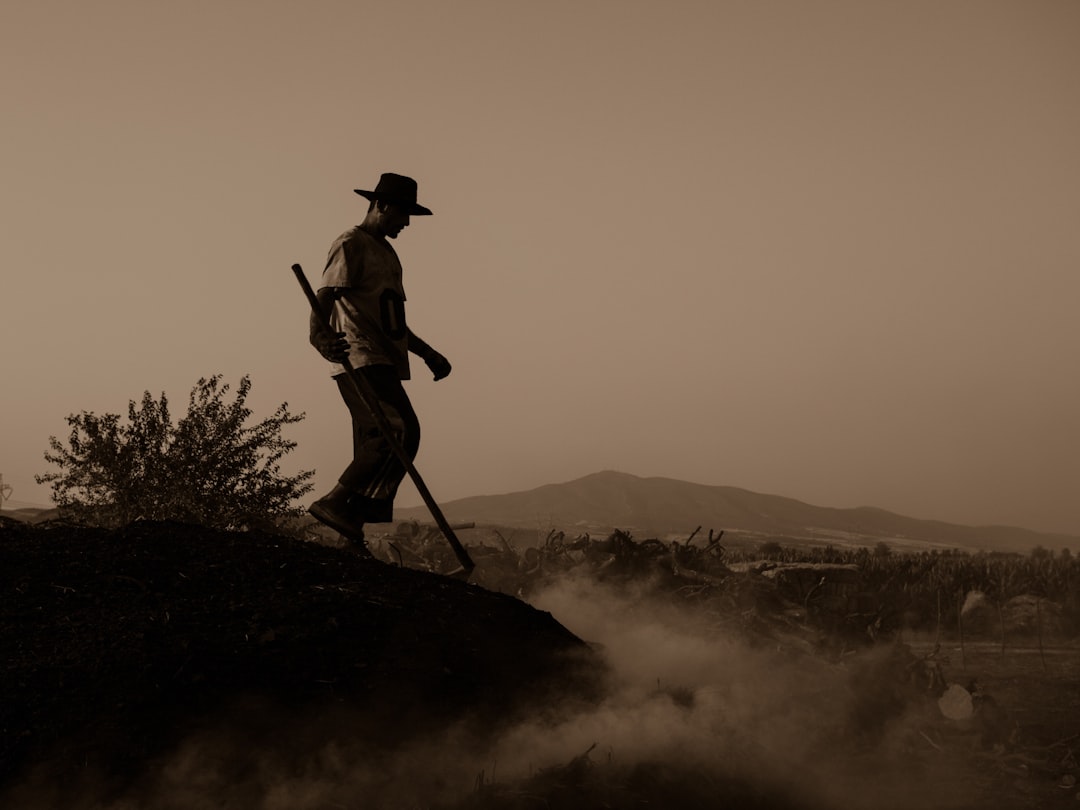 man in black hat standing on rock formation during daytime