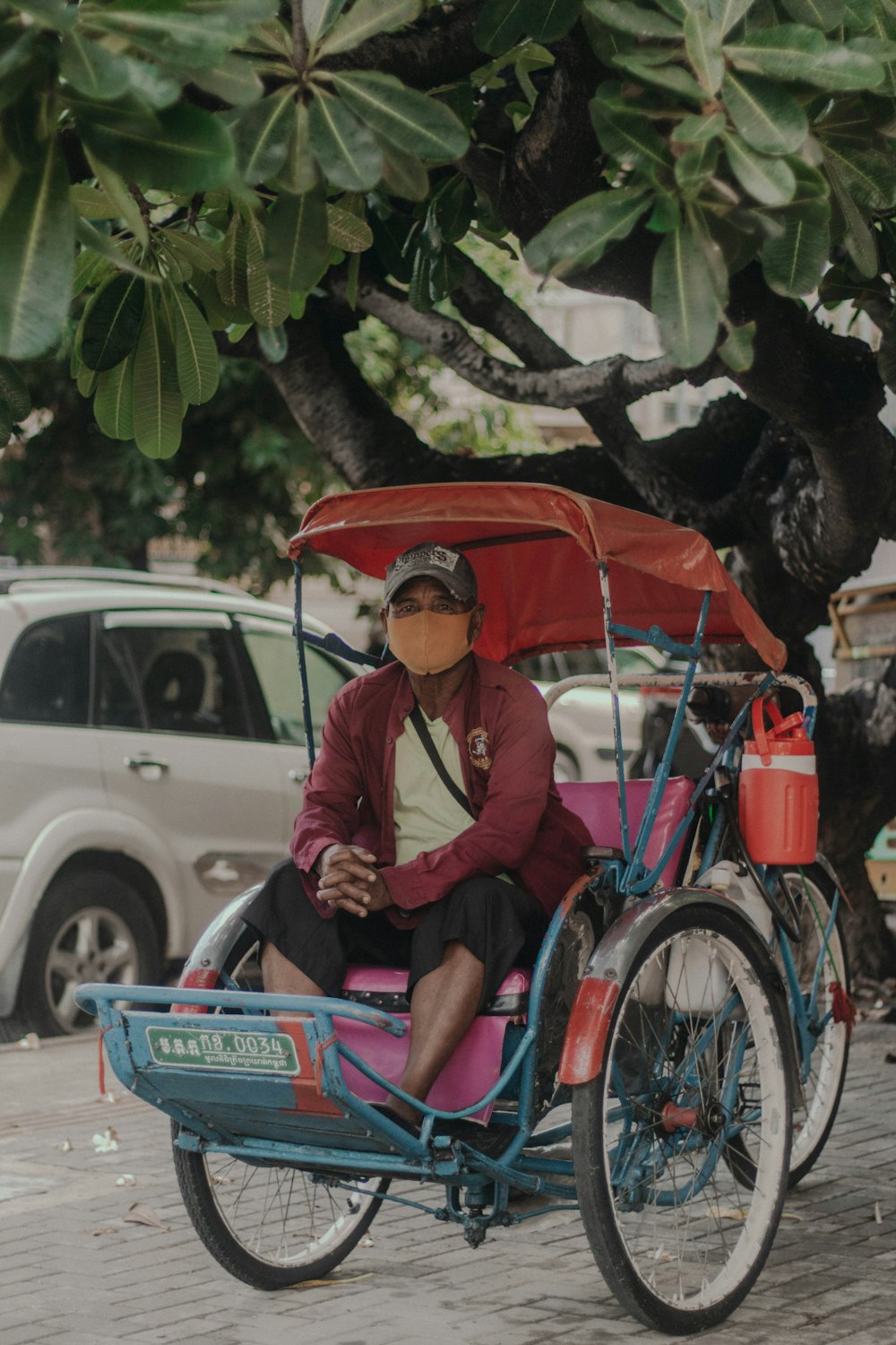 man in pink dress shirt sitting on red and blue trike