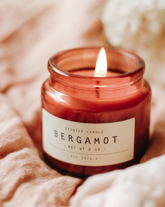 A chic, sophisticated scented candle glowing softly on a polished marble surface.