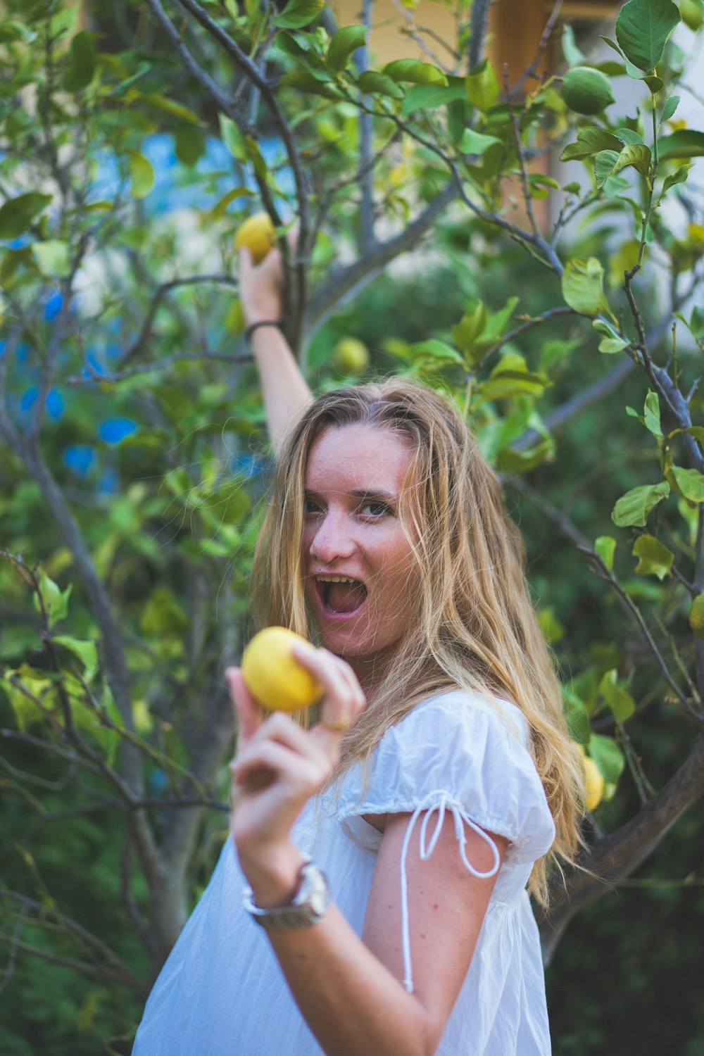 mulher na camisa branca que segura a fruta amarela