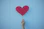 person holding heart shaped red balloon