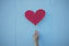 person holding heart shaped red balloon