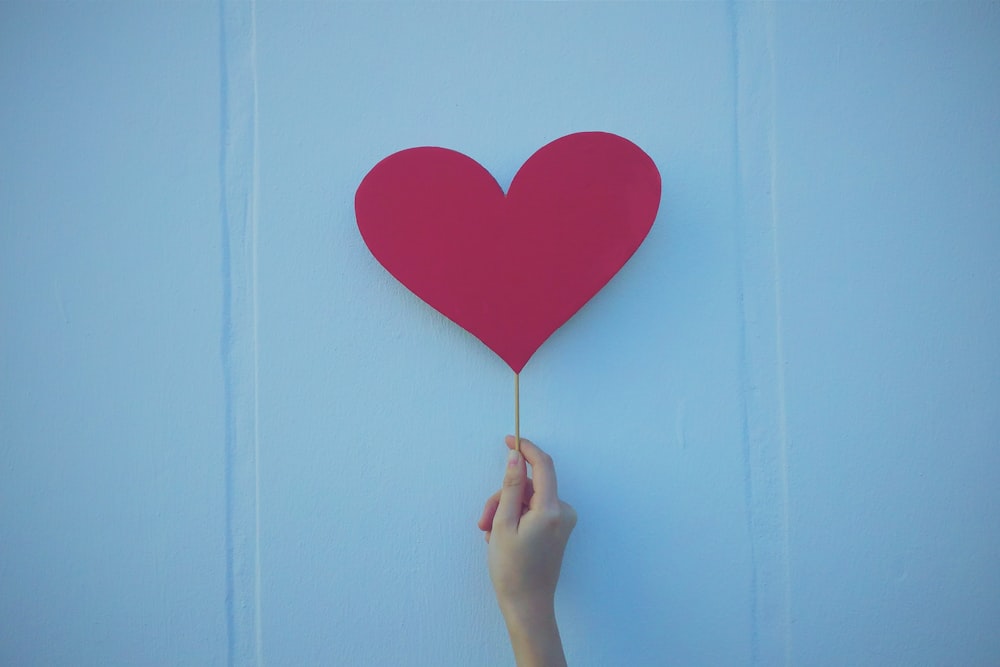 pessoa segurando o balão vermelho em forma de coração